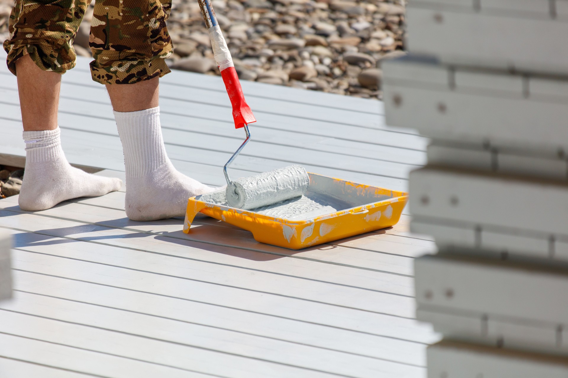 A man is painting a deck with a roller